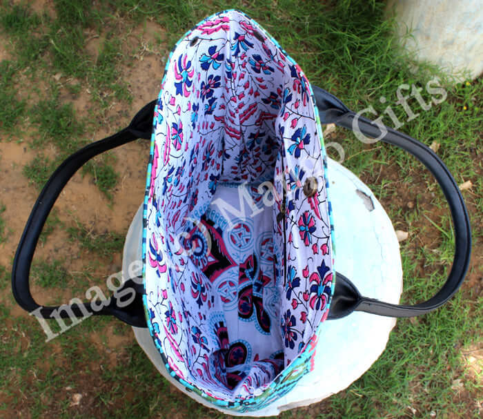 Interior view of a blue geometric tote bag with floral design, featuring leather straps and one zip pocket.